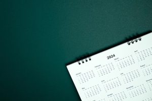 A simple coil bound year calendar set slightly askew on a dark green tabletop.