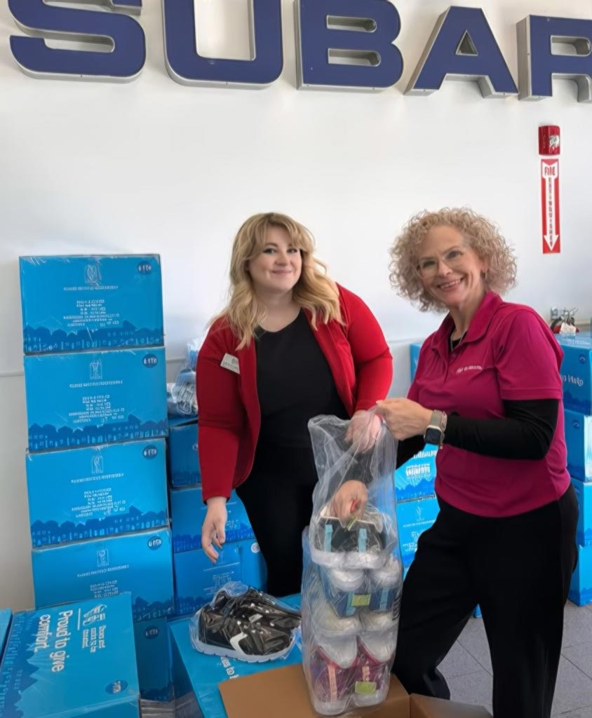 2 ladies bagging up pairs of brand new shoes for donation